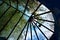 Blue sky and tree branches through an old-style stained glass window, a semicircle of glass