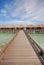 Blue sky turquoise water wooden bridge walkway leading to a Row of Overwater Villa at a resort island, Maldives