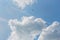 Blue sky with white clouds, contrails and black bird