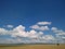 Blue sky with white clouds. Field with electric polls