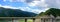 The blue sky, white clouds, green mountains and lake water, the cars driving out of the tunnel are speeding on the viaduct