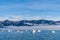 Blue sky, white clouds, mist & aquamarine seas at Akaroa Harbor. Anchored are fishing boats & sailboats, along the Port at Akaroa