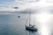 Blue sky, white clouds, mist & aquamarine seas at Akaroa Harbor. Anchored are fishing boats & sailboats, along the Port at Akaroa