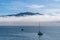 Blue sky, white clouds, mist & aquamarine seas at Akaroa Harbor. Anchored are fishing boats & sailboats, along the Port at Akaroa