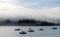 Blue sky, white clouds, mist & aquamarine seas at Akaroa Harbor. Anchored are fishing boats & sailboats, along the Port at Akaroa