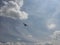 blue sky with white clouds and the silhouette of an airplane