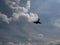 blue sky with white clouds and the silhouette of a plane