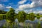 Blue sky, white clouds. Trees are reflected in the water