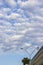 Blue sky with white cumulus clouds. Part of the building at the bottom of the frame