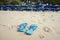 The blue slippers on the beach with white sand, against the backdrop of sun loungers with umbrellas.