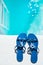 Blue slippers near swimming pool at poolside. Summer vacation. Blue sandals by swimming pool. Blue sea surface with waves, textur