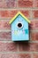 Blue small cue wooden bird house hanged on brick wall