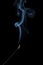 Blue smoke fragrant curls picturesquely rise above a smoldering incense stick on a black background. Fragrant Sandalwood for