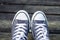 Blue sneakers on the feet on wooden background. Top view