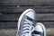 Blue sneakers on the feet on wooden background. Top view