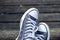 Blue sneakers on the feet on wooden background. Top view