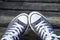 Blue sneakers on the feet on wooden background. Top view