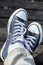 Blue sneakers on the feet on wooden background. Top view