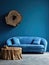 Blue sofa made of tree trunk root over blue empty wall with copy space. Rustic interior design of modern living room