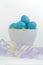 Blue speckled eggs in Easter grass with pastel ribbon