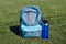 blue sports bottle and blue sports backpack on green stadium cover