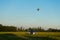 Blue sports car in a field and aerostat balloon at background