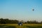 Blue sports car in a field and aerostat balloon at background