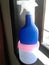 A blue spray bottle of room cleaner on a pink tupperware