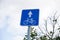 Blue square road sign Lane for cyclists close - up on sky background with clouds, tree