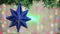 A blue star hangs on a branch on the left on New Years night.