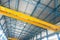 Blue steel frame of metal industrial roof in warehouse with yellow cranes