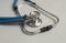 Blue stethoscope on gray medical desk, close up