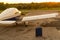 A blue suitcase and a parked small private jet. Quadruple plane with a propeller for an air taxi in the sunset. Self