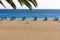 Blue sunbeds and umbrellas on empty beach in Puerto del Carmen, Lanzarote