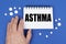 On the blue surface of the tablet, a hand and a notepad with the inscription - ASTHMA