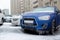 The blue SUV and other cars stand in the city frozen and icy from the rain in winter. Blocked by ice.