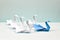 A blue swan leads a flock of white swans. Paper swans on a blue background. Origami. Leadership concept.