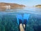 Blue swimfins on female legs in crystal clear water of Kolona double bay Kythnos island Cyclades Greece, Aegean sea.