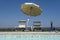 Blue swimming pool with beach lounger with parasol, sun deck on sea view for summer vacation