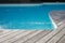 Blue swimming pool with exotic wooden terrace in teak natural flooring and blue water