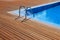 Blue swimming pool with teak wood flooring