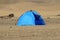 Blue tent against dessert dunes.