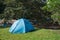 Blue tent camping on lawn in tropical rainforest