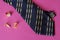 Blue tie with yellow stripes, gold ring and cufflinks on a pink