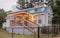 Blue tiny house in the country with warm porch lighting and a black chain fence around the yard