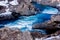 Blue, torrential river surrounded by lava rock