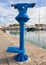 Blue tourist monocular for sightseeing on the background of yachts standing in the marina of the seaside town