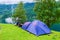 The blue tourist tent is set near Geiranger on the Geirangerfjord shore at the background of the cruise liner. Summer trip to