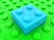 Blue toy brick against the background of green toy bricks
