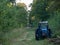 Blue tractor abandoned in a forest alley